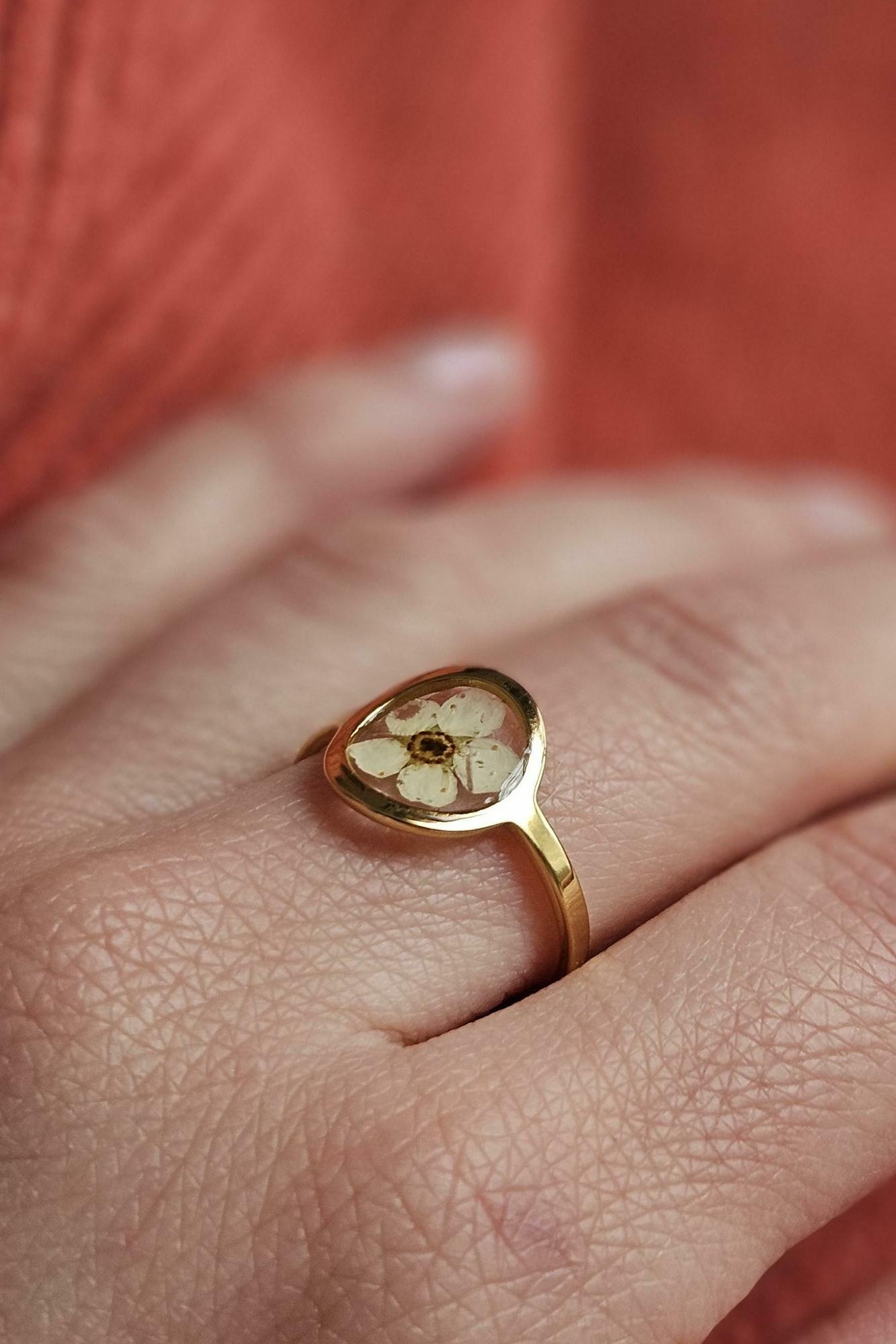bague resine UV epoxy minimaliste rond ovale dorée avec une fleur préssée et séchée
