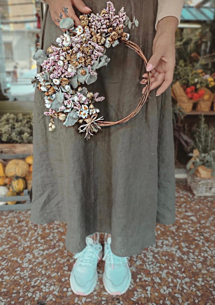 ghirlanda di fiori secchi dai colori pastello intrecciati su una base rustica di vimini